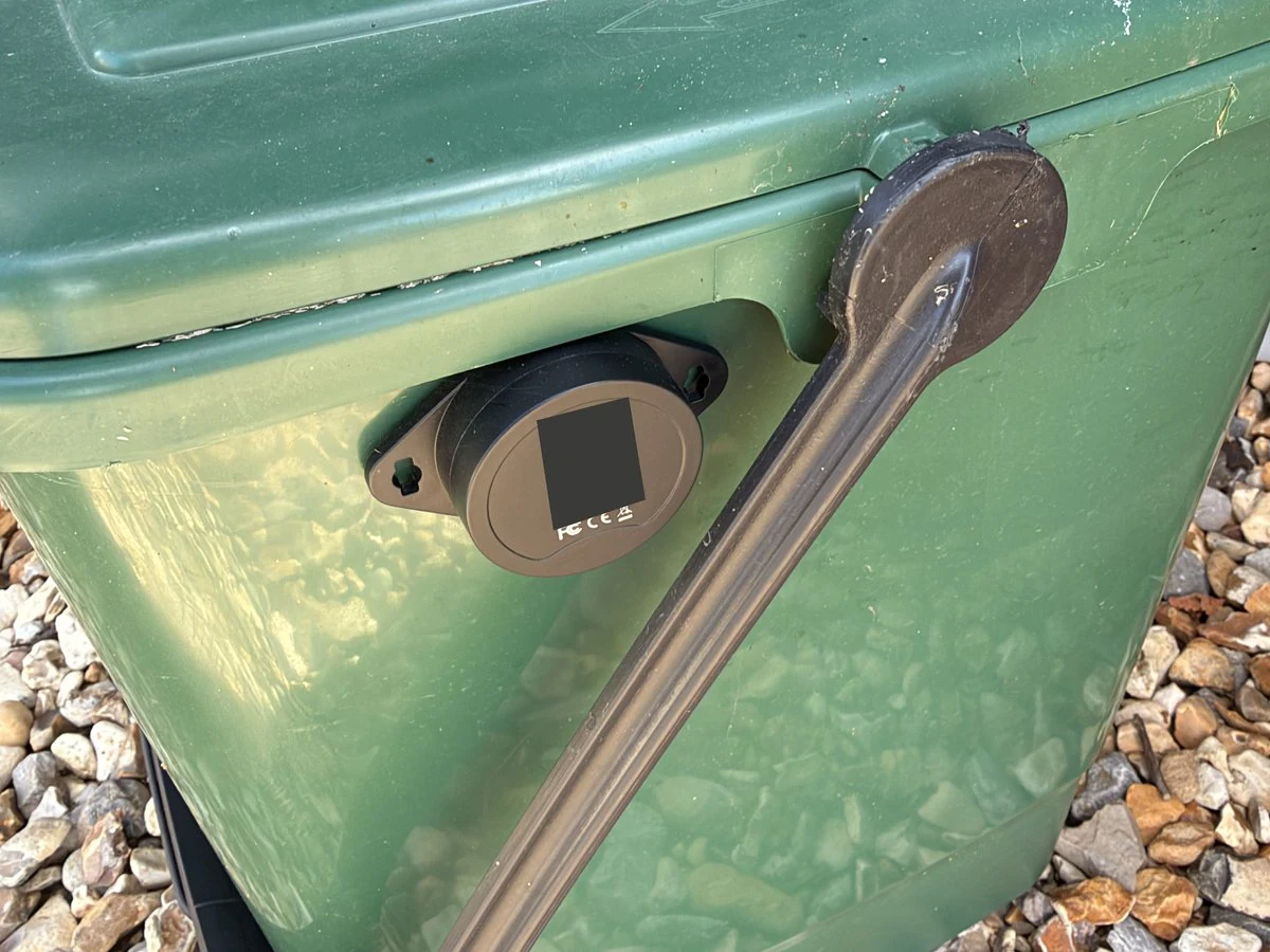 A KKM K4W tag attached to the food caddy beside its carrying handle, with its identifying label obscured.