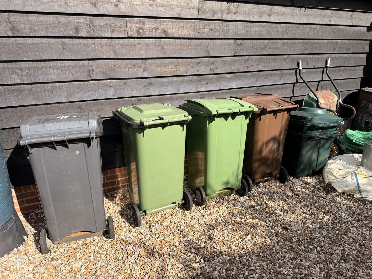 The row of household bins beside a wooden wall in the BinRange installation.